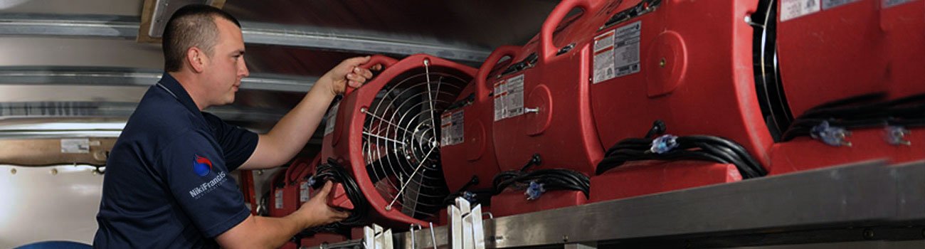 A water damage technician preparing equipment for structural drying
